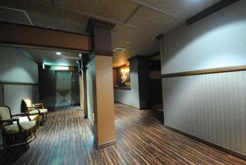 a room with a hallway with chairs and a wall at ホテル マリオン 鈴鹿 in Suzuka