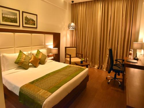 a hotel room with a bed and a desk and a chair at Comfort Inn Donil Vadodara in Vadodara