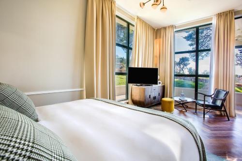 a bedroom with a bed and a tv and windows at Hotel Brown Beach House & Spa in Trogir