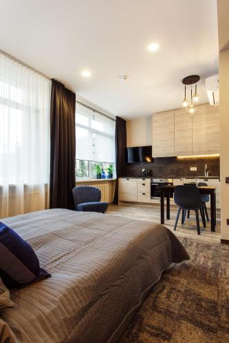 a bedroom with a bed and a desk and a kitchen at Old Town Trio Apartments in Vilnius