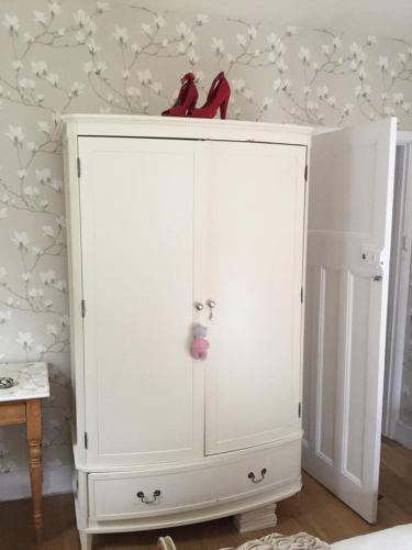 a white cabinet with a pair of red shoes on top at Hurstbourne in Camberley