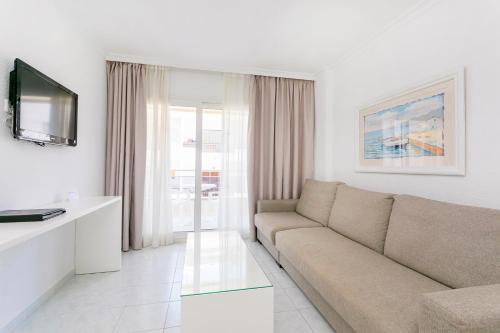 a living room with a couch and a tv at Aparthotel Duquesa Playa in Santa Eularia des Riu