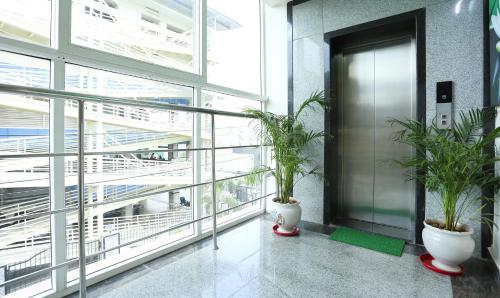 a lobby with two potted plants and a elevator at Treebo C Plaza in Vijayawāda
