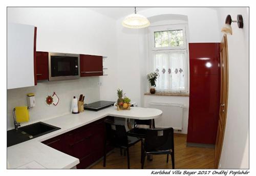 cocina con encimera blanca y armarios rojos en Apartmán Vila Bayer, en Karlovy Vary