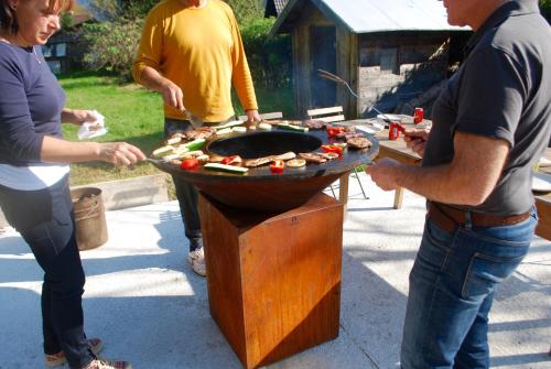 a group of people cooking food on a grill at Country House Trata in Kranjska Gora