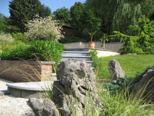 a garden with some rocks and a retaining wall at Chambre d'hotes du Tailfer in Lustin