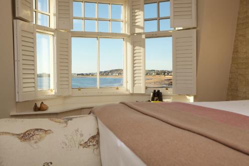 a bedroom with windows with a view of the ocean at The Ship Inn in Elie