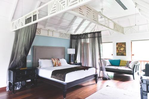 een slaapkamer met een bed en een bank in een kamer bij Indian Summer House in Mūvattupula