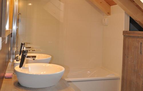 a bathroom with two sinks and a bath tub at Odalys Chalet Le Mas des Neiges in Valloire