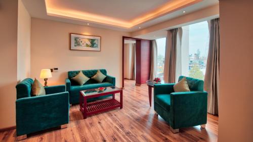 a living room with two green chairs and a table at Golden Tulip Essential Jaipur in Jaipur