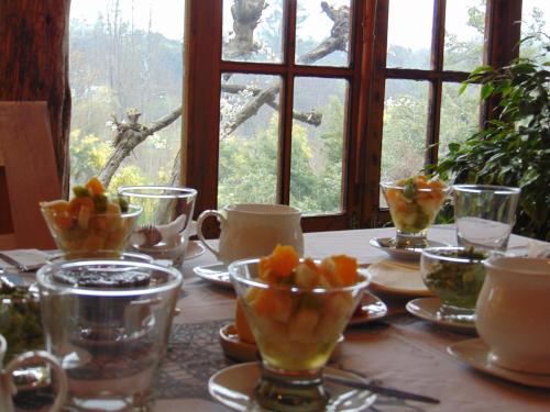 a table with cups and bowls of fruit on it at Cabañas Puente Negro in Puente Negro
