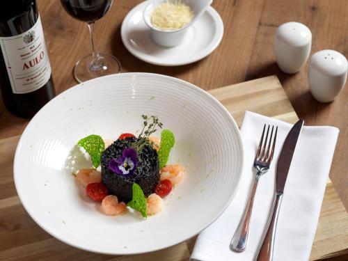 a plate of food on a table with a bottle of wine at Hotel Parc Plaza in Luxembourg