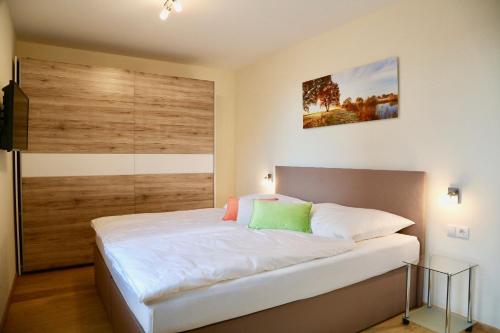 1 dormitorio con 1 cama blanca grande y pared de madera en Nikolaier Weinblick - Ferienwohnung Muskateller, en Sankt Nikolai ob Draßling