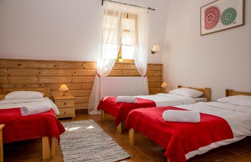 a room with three beds with red sheets and a window at Kurpiowska Kraina in Wydmusy