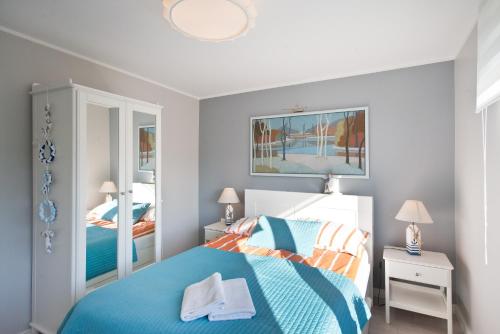 a bedroom with a blue bed and a mirror at Pomorskie Apartamenty Ceynowy 1 Deluxe in Sopot