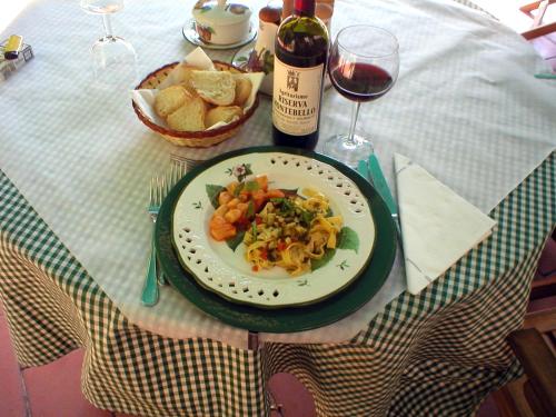 una mesa con un plato de pasta y una copa de vino en La Riserva Montebello, en Bolsena