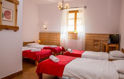 four beds in a room with red and white sheets at Kurpiowska Kraina in Wydmusy