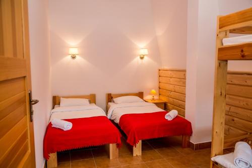 two beds in a room with red cushions at Kurpiowska Kraina in Wydmusy