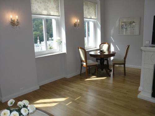 ein Esszimmer mit einem Tisch und Stühlen sowie 2 Fenstern in der Unterkunft Apartmán LUX Škroupova in Karlsbad