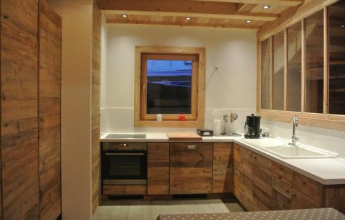 a kitchen with wooden cabinets and a sink and a window at Odalys Chalet le Pure Altitude in Valloire