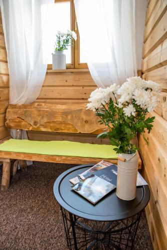 a room with a bench and a table with flowers at Kurpiowska Kraina in Wydmusy