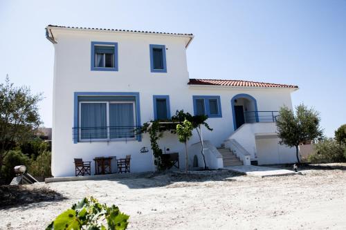 a white house with blue windows and stairs at Romanos Xi in Xi
