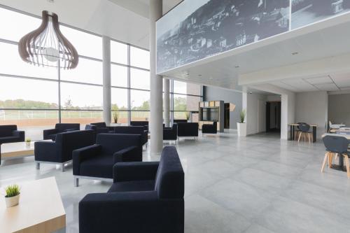 a waiting room with blue chairs and tables and windows at B&B HOTEL Longwy Porte du Luxembourg in Longwy