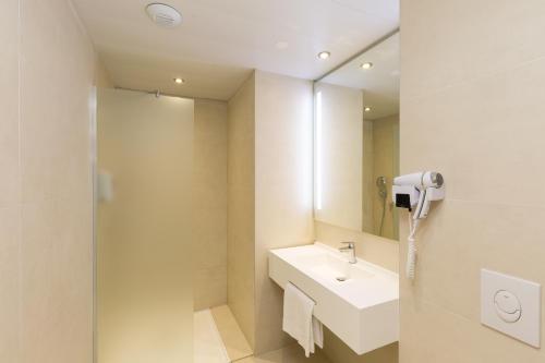 y baño con lavabo y espejo. en B&B HOTEL Longwy Porte du Luxembourg en Longwy