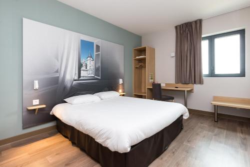 a hotel room with a large bed and a desk at B&B HOTEL Longwy Porte du Luxembourg in Longwy