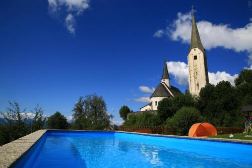 a church and a swimming pool in front of a church at Urlaub am Lacknerhof - Familie Klocker in Liebenfels