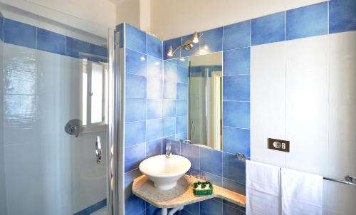 Baño de azulejos azules con lavabo y espejo en Hotel Stella Maris, en Capoliveri