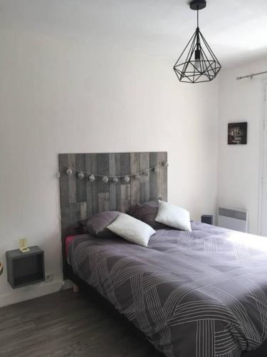 Schlafzimmer mit einem Bett mit einem Kopfteil aus Holz in der Unterkunft Charmant appartement - Centre d'Arcachon in Arcachon