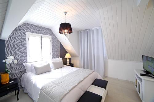 a bedroom with a large white bed and a window at Vila de Charme Suítes in Campos do Jordão