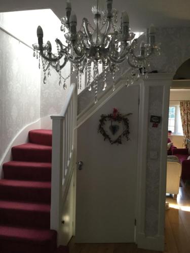 a chandelier hanging over a white door with stairs at Hurstbourne in Camberley