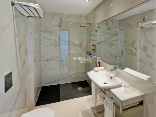 a white bathroom with a sink and a shower at Alisios in Albufeira