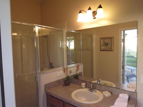 a bathroom with a sink and a shower and a mirror at Kissimmee Area Pool Home in Orlando