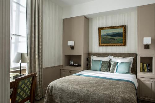 a bedroom with a bed and a desk and a window at Hôtel des Saints Pères - Esprit de France in Paris