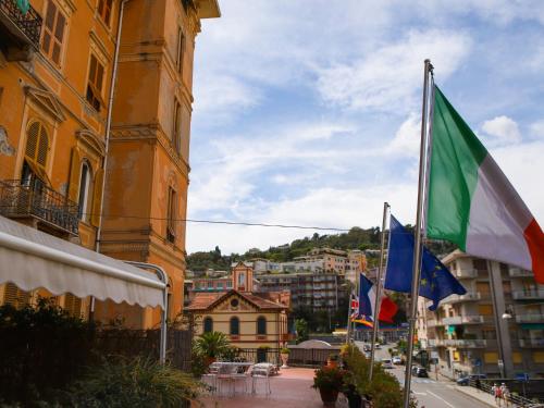 a building with flags in front of a city at Hotel Portofino in Rapallo