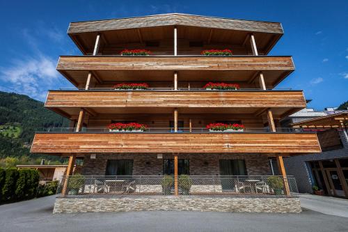 a building with a balcony with red flowers on it at Aktivhotel Tuxerhof in Zell am Ziller