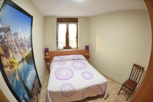a small bedroom with a bed and a large painting at Apartamentos Rurales Los Solares in Mogro