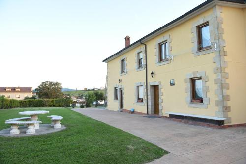 a yellow building with a picnic table in the grass at Apartamentos Rurales Los Solares in Mogro