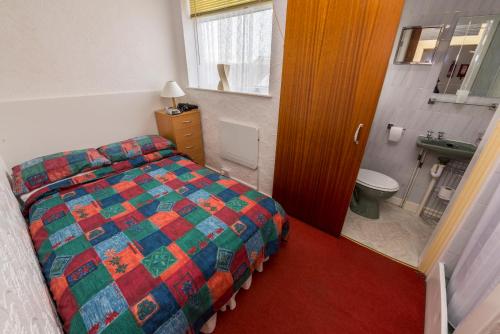 een slaapkamer met een bed en een badkamer met een wastafel bij Lyndale Holiday Flats in Blackpool