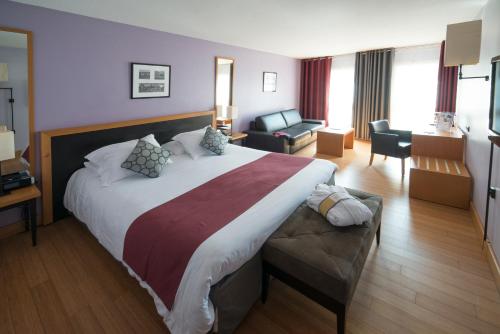モンペリエにあるメルキュール モンペリエ センター アンティゴーヌの大きなベッドとリビングルームが備わるホテルルームです。