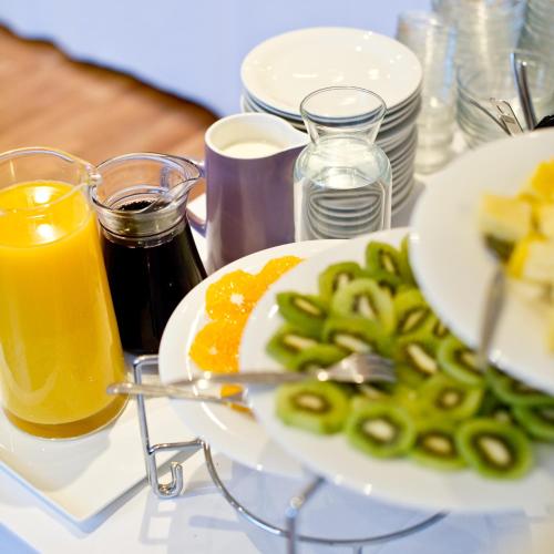 a table with a plate of food and glasses of orange juice at Burgblickhotel in Bernkastel-Kues
