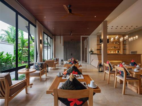 a restaurant with wooden tables and chairs and large windows at De Malee Pool Villas in Ao Nang Beach