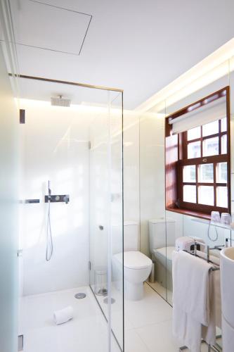 a bathroom with a glass shower and a toilet at Oca Ribeira do Porto Hotel in Porto