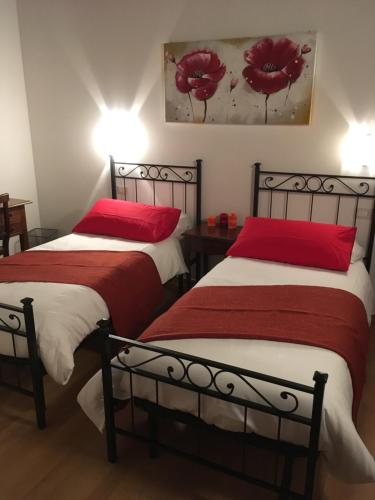two beds with red pillows in a room at Farm stay Al Pisoler in Caneva