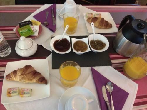 einen Tisch mit einem Frühstück mit Croissants und Orangensaft in der Unterkunft Maison MARYSA in Mérignac