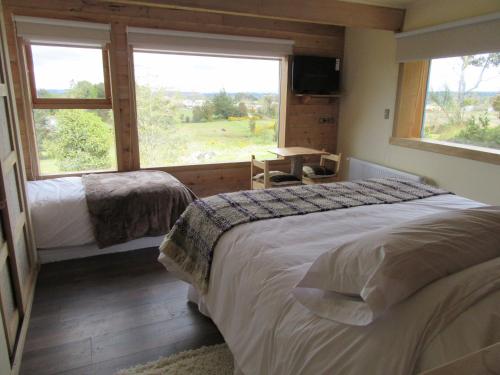a bedroom with two beds and a large window at Casa Bosque Chiloé in Dalcahue