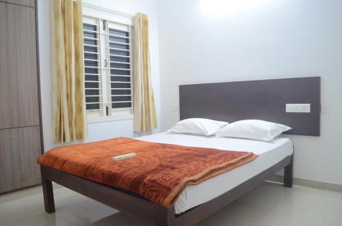 a bedroom with a bed with a orange blanket on it at Blackroots Serviced Apartments in Coimbatore